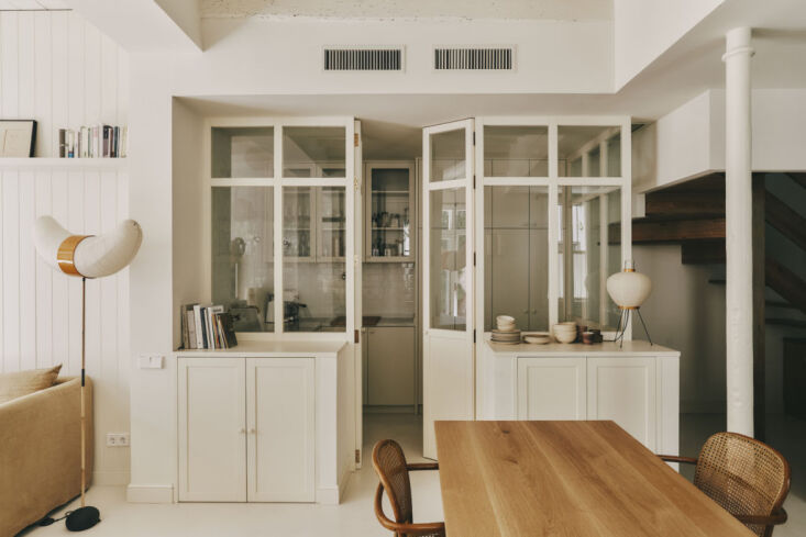 A clean, modern laundry and pantry room with integrated storage and wood accents.