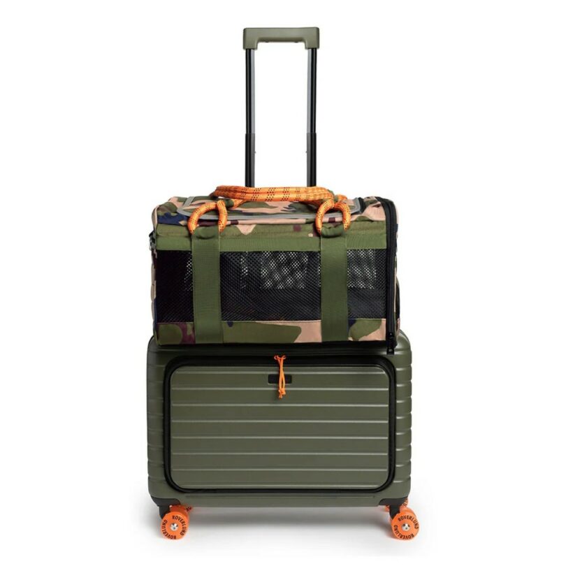 A camouflage pet carrier securely attached to a green rolling suitcase with bright orange accents.
