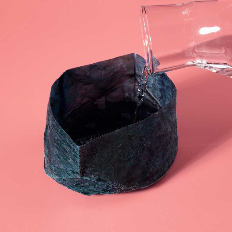 Water being poured into a blue-tinted edible bowl to test its integrity.