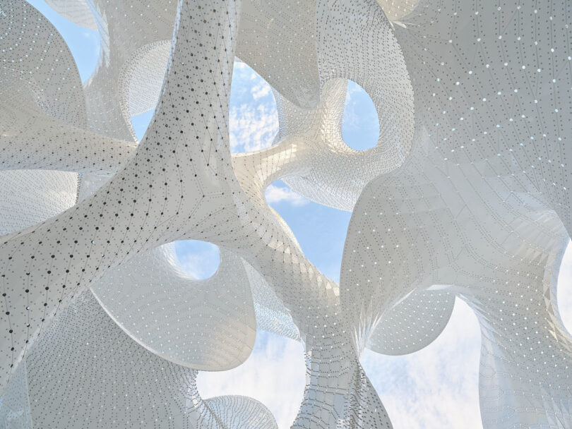 Close-up of the Orb's white perforated surface against a blue sky, showing the intricate assembly of aluminum pieces.
