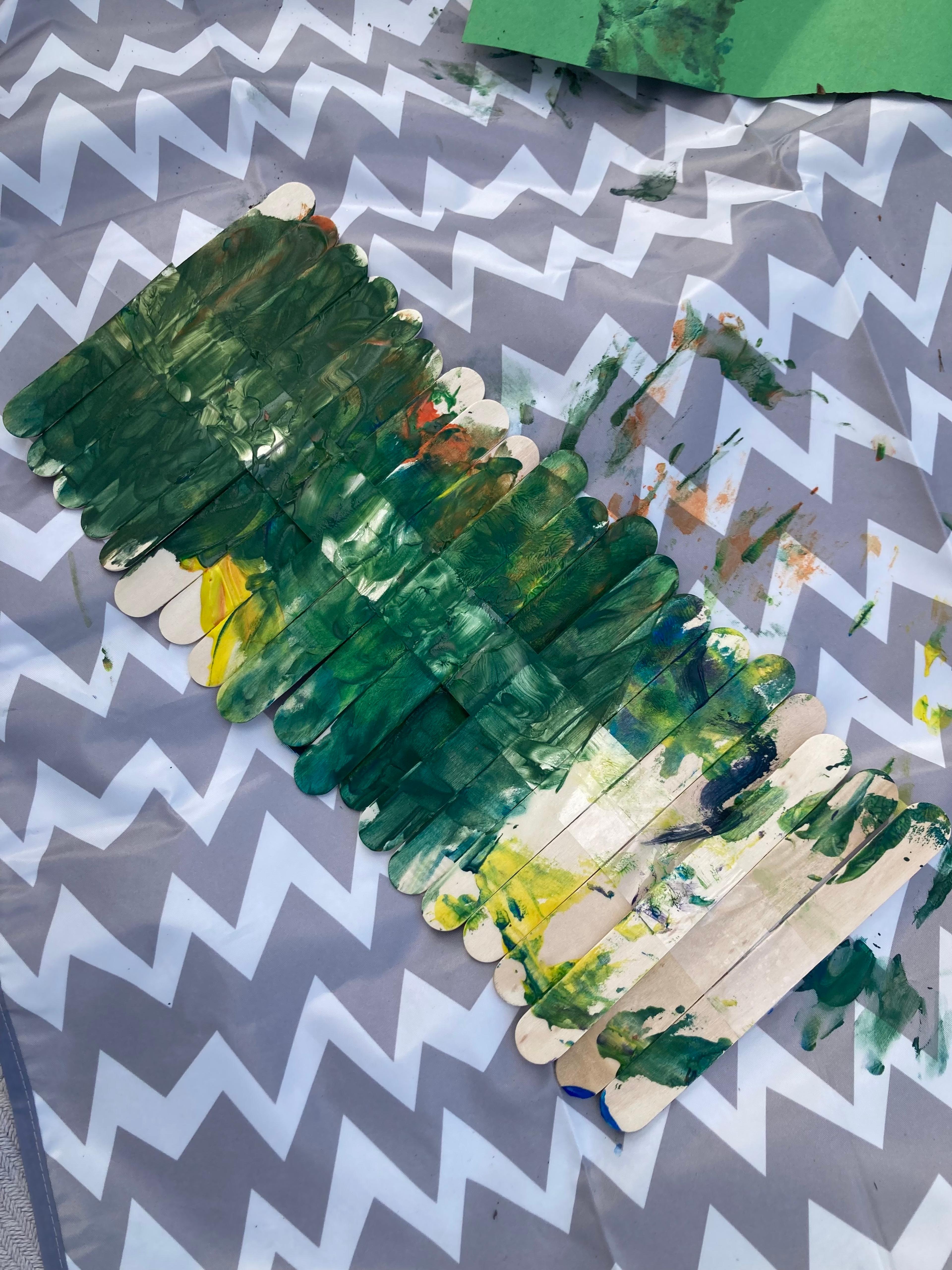 Colorful decorated popsicle sticks used as plant labels in a garden bed.