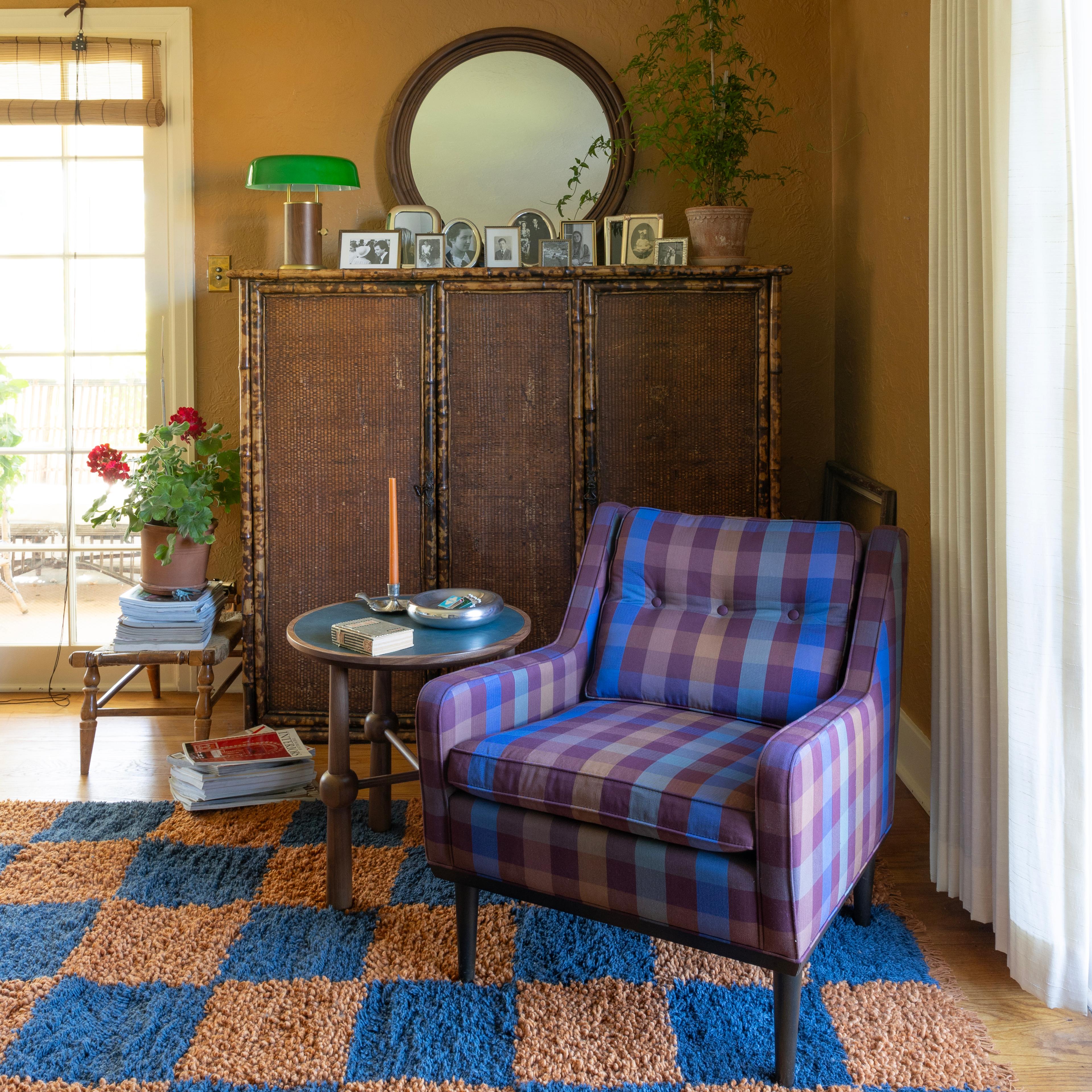 A reading corner with a patterned armchair, a bookshelf, and a decorative mirror.