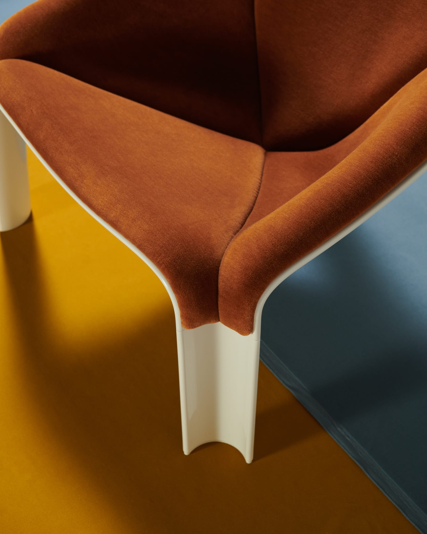 Side profile of a white F300 chair with blue upholstery in a sunlight-drenched room.