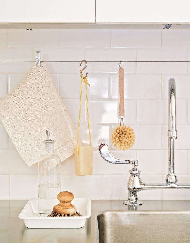 A white enamel tray by Noda Horo used to organize small kitchen items on a counter.
