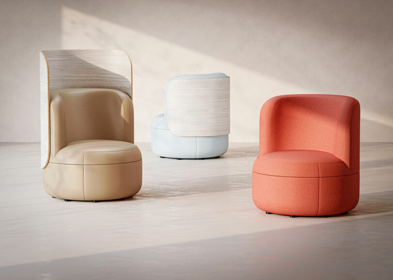 Three upholstered chairs in beige, light blue, and coral pink in a bright, neutral room.