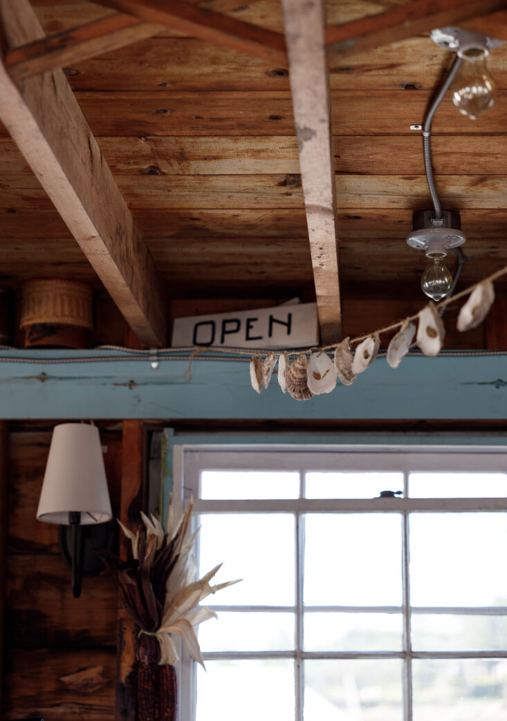 Close-up of handmade oyster shell strings and vintage wooden kitchen tools hanging on a wall.