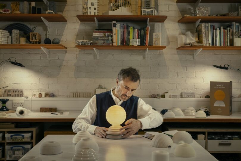 A designer in a studio environment assembling the ceramic components of a round lamp.