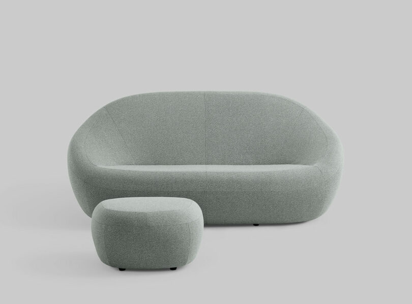 A light gray curved modern sofa and matching ottoman by Jean Nouvel for Coalesse.