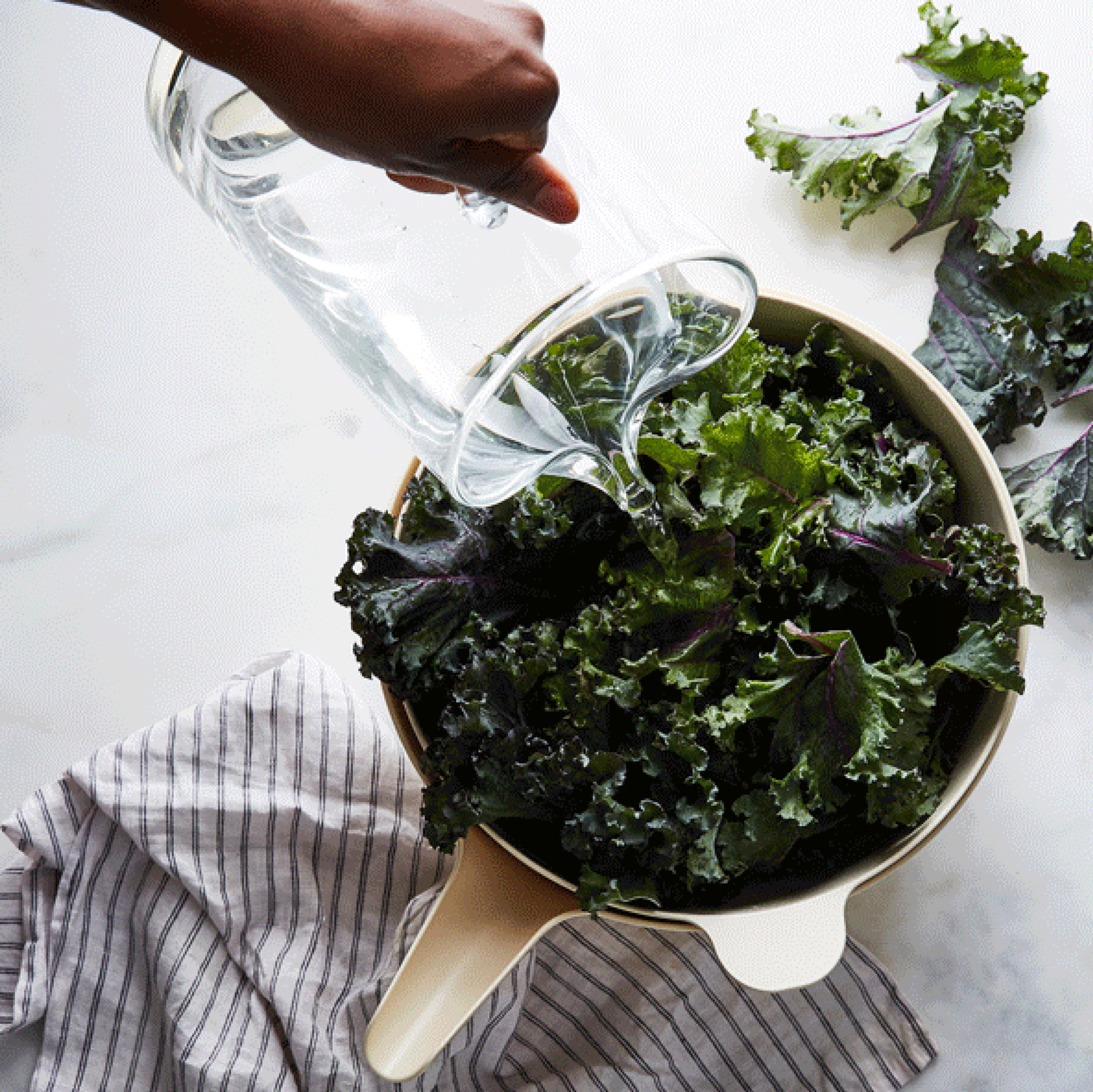 Fresh green lettuce leaves being washed in a simple white ceramic bowl filled with water.