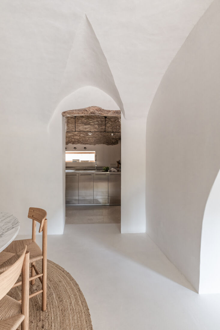 An interior shot of the farmhouse showing new microcement floors meeting original stone walls.