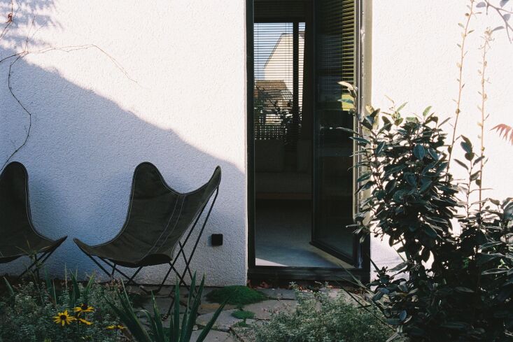 Two classic butterfly chairs placed outside the entrance of the guest apartment featuring textured render walls.
