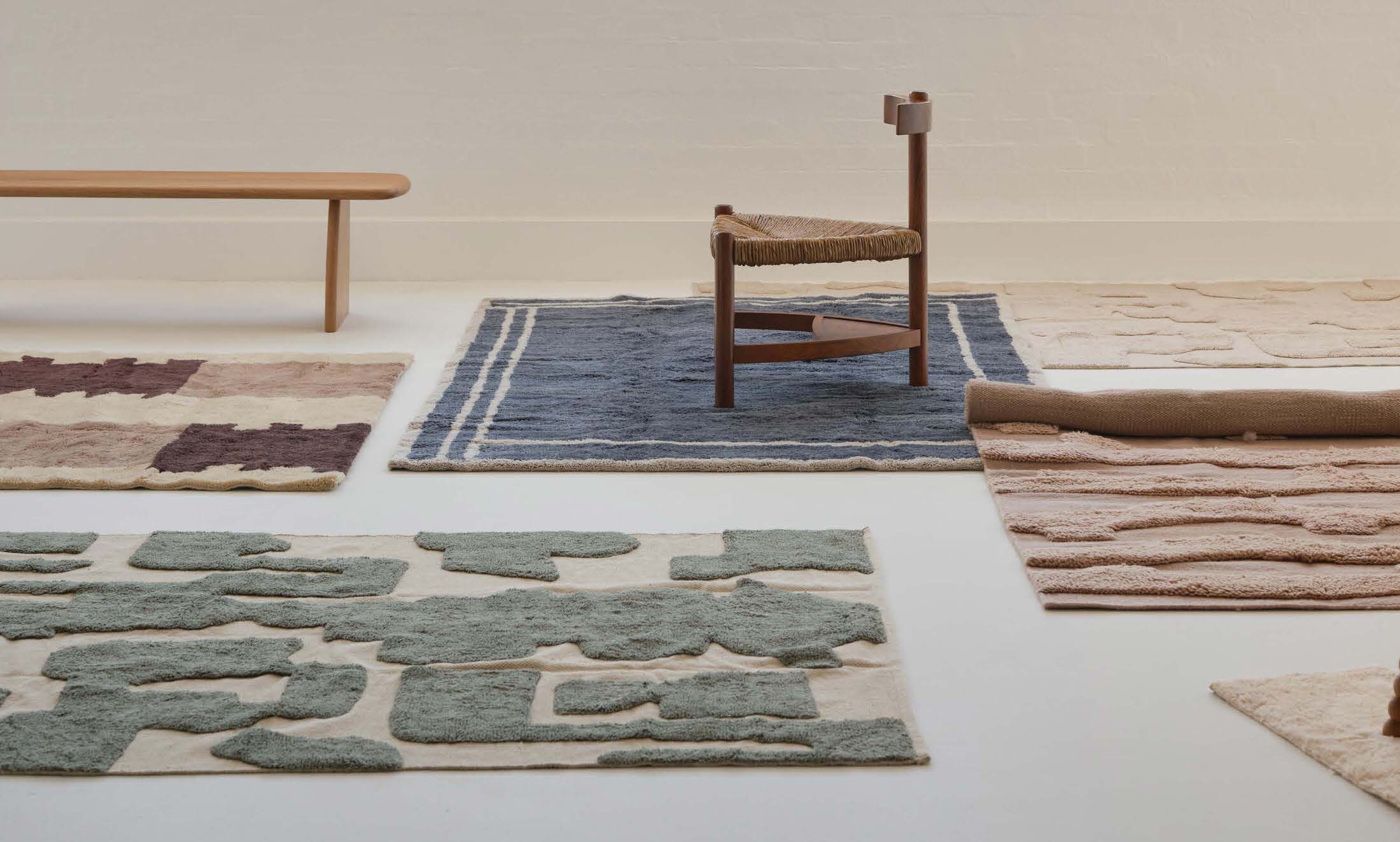 A cozy room setup showing a large rug layered with simple furniture to create a grounded feel.
