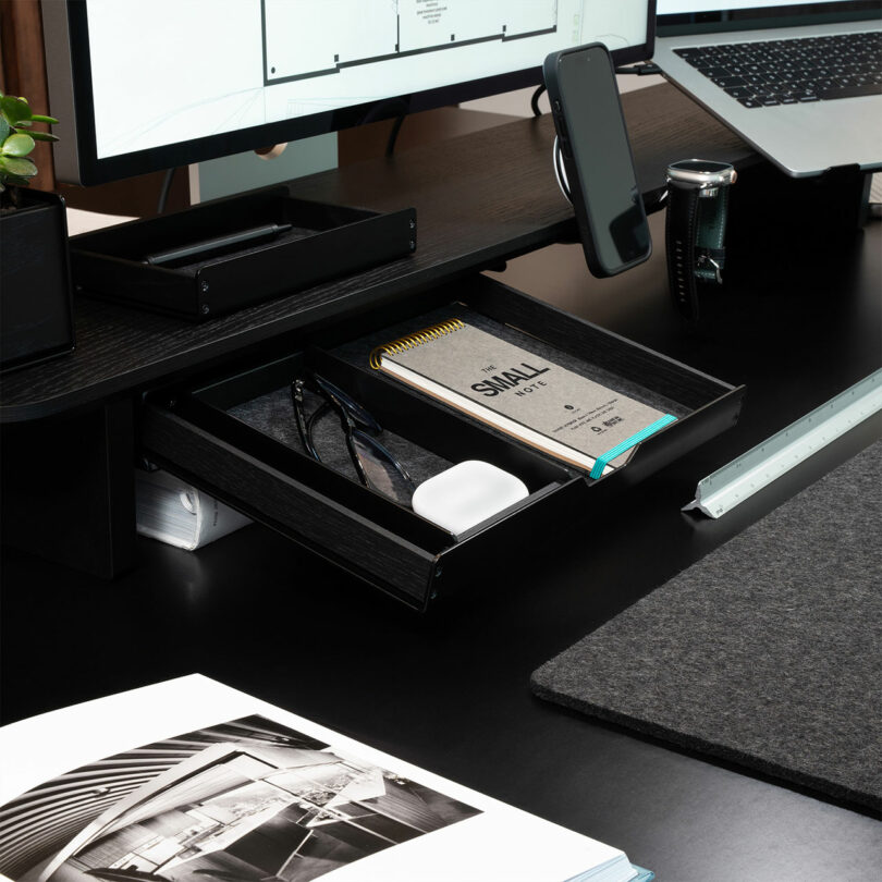Close-up of Balolo accessories including a phone holder and a wooden drawer attached to the monitor stand.