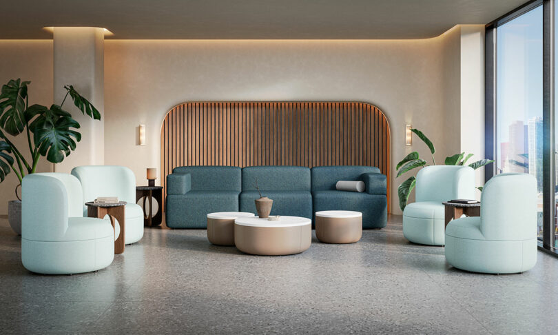 Modern office lounge with blue seating, round tables, and city views through large windows.