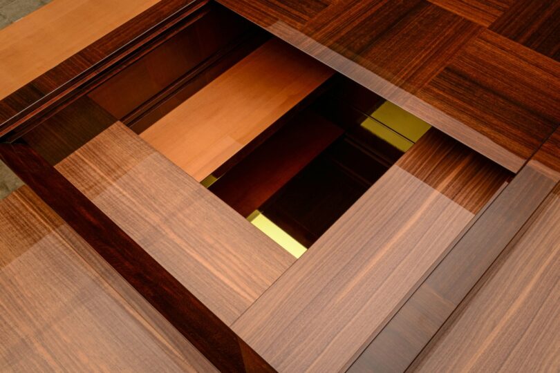 Close-up of a geometric wooden structure with overlapping panels and gold-toned recessed accents.