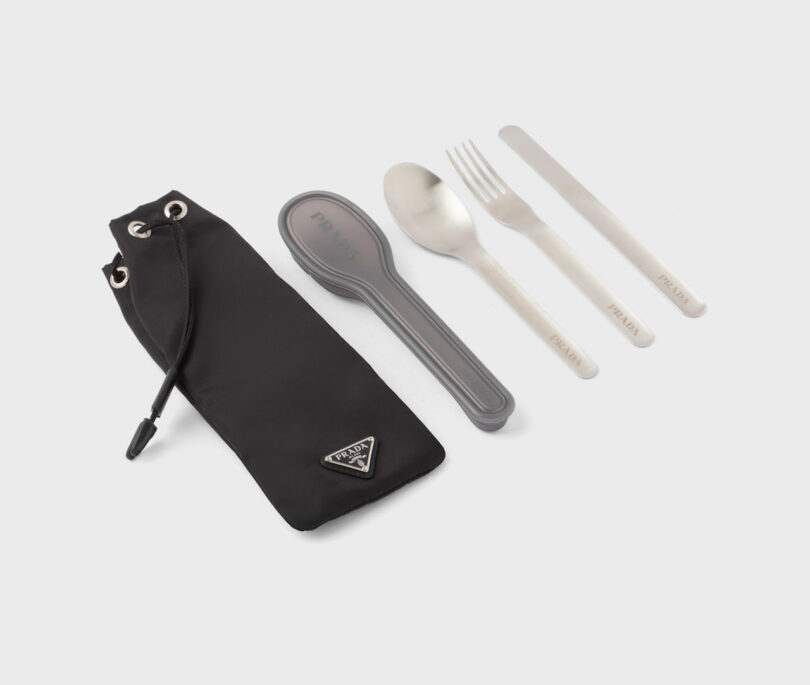 Stainless steel fork, spoon, knife, and straw set next to a black Re-Nylon carrying pouch.
