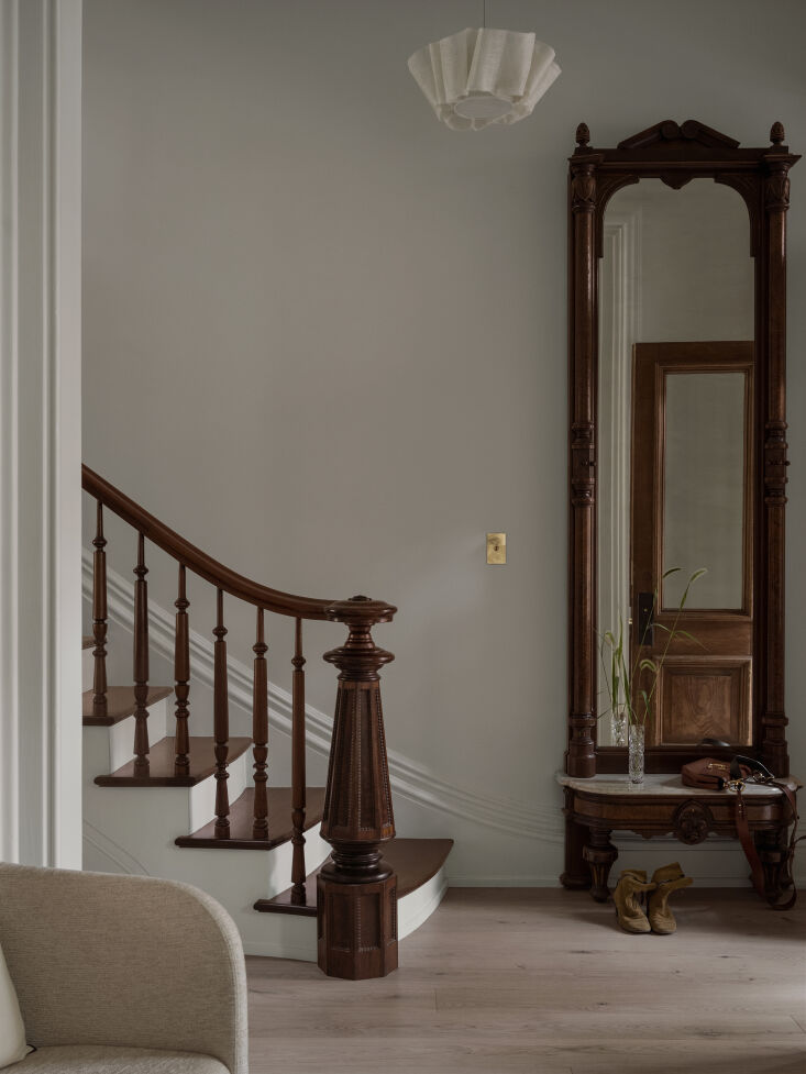Restored original brownstone staircase and mirror paired with a modern pleated pendant lamp.