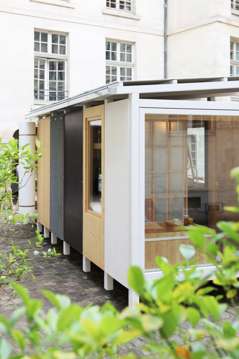 A modern modular building with wood and metal panels in a courtyard setting