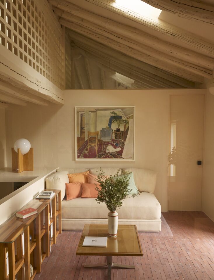 A minimalist L-shaped wooden bench with thin cushions in a corner with geometric wall details.