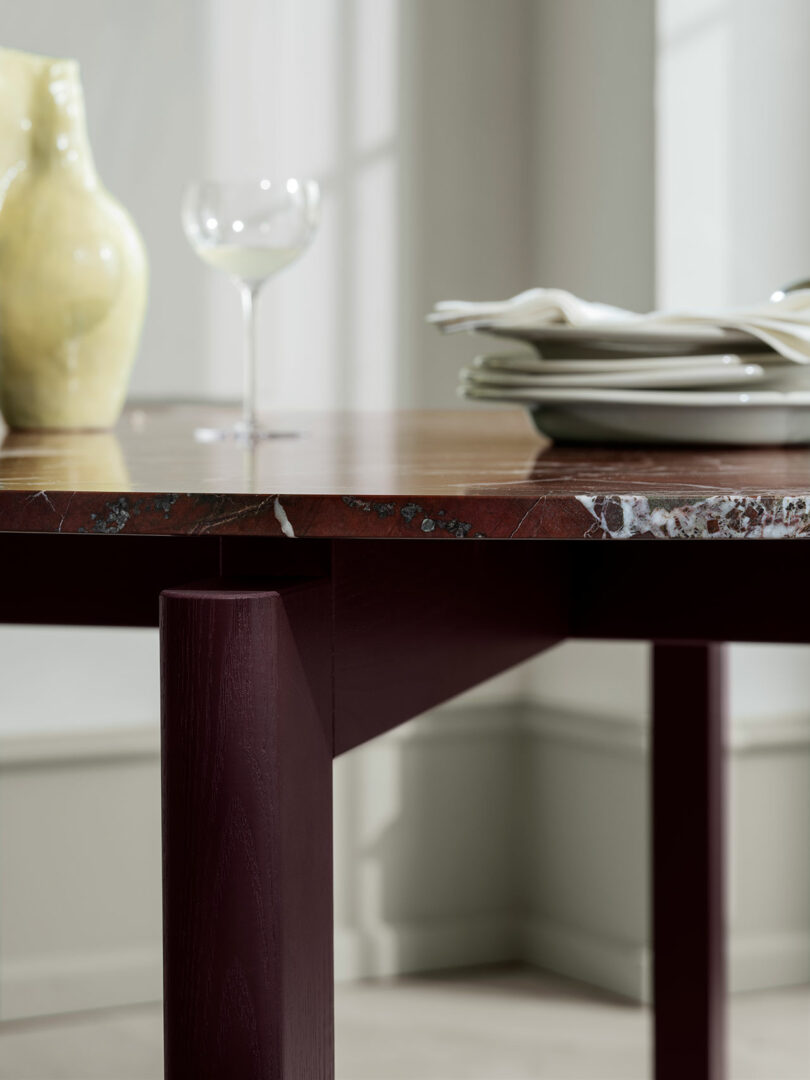 Detail shot of the marbled table edge with minimalist dining accessories in a bright room.