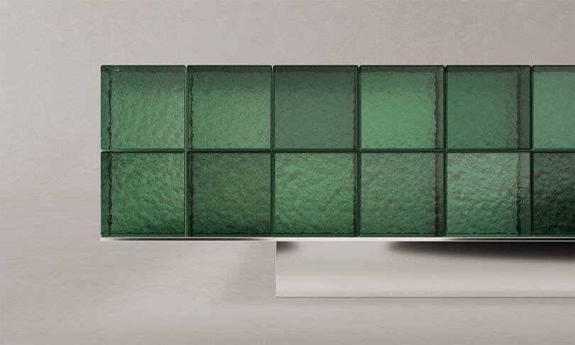 Detail view of a green textured glass tabletop meeting a metallic rectangular support base.