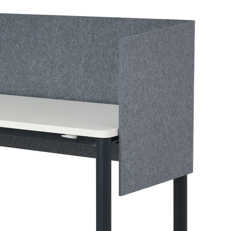 A light wood desk with a gray fabric privacy screen wrapped around three sides of the tabletop.