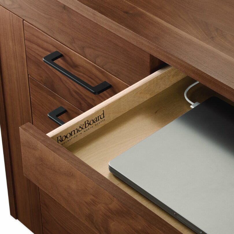 A wooden drawer on the Lincoln desk partially open to reveal a laptop, with Room & Board branding visible.