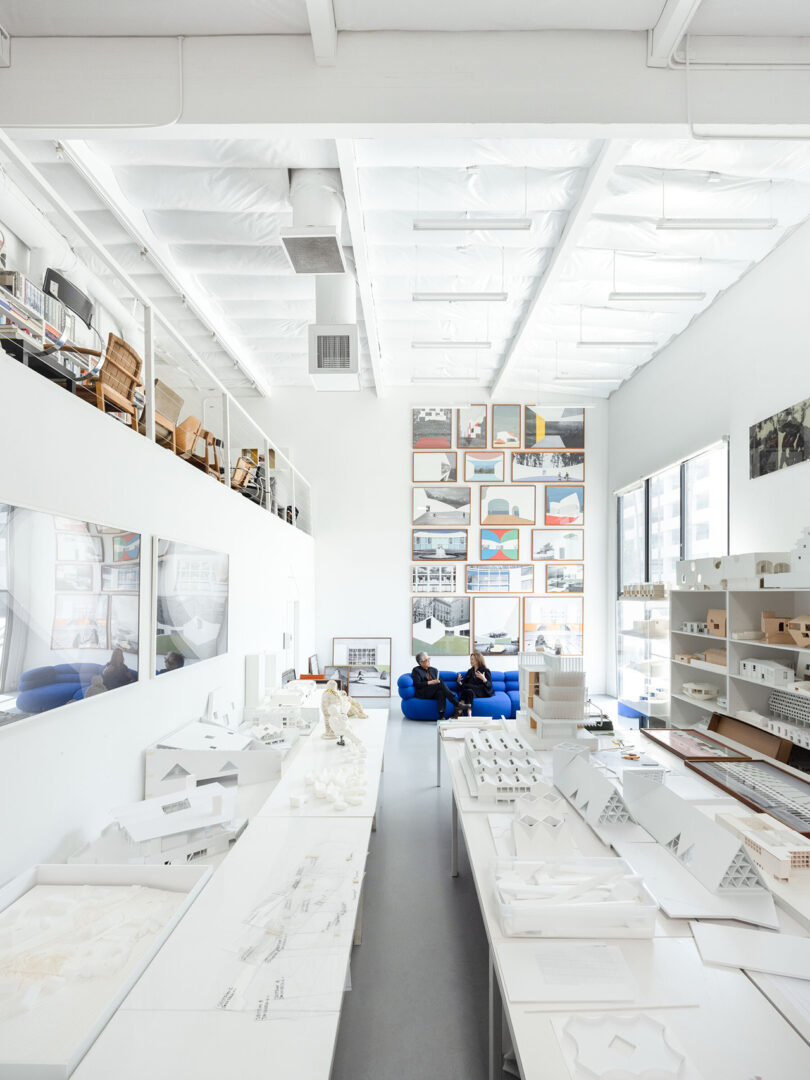 A bright architecture studio filled with models, material samples, and natural light.