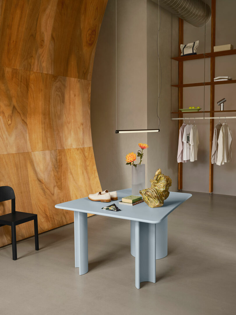 A light blue Re-norm Table used as a display surface for books, sculptures, and daily items in a modern interior.