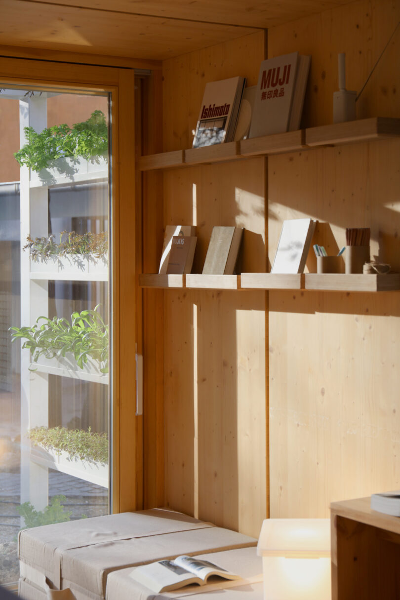 A wooden reading nook inside a modular house with a view of greenery outside