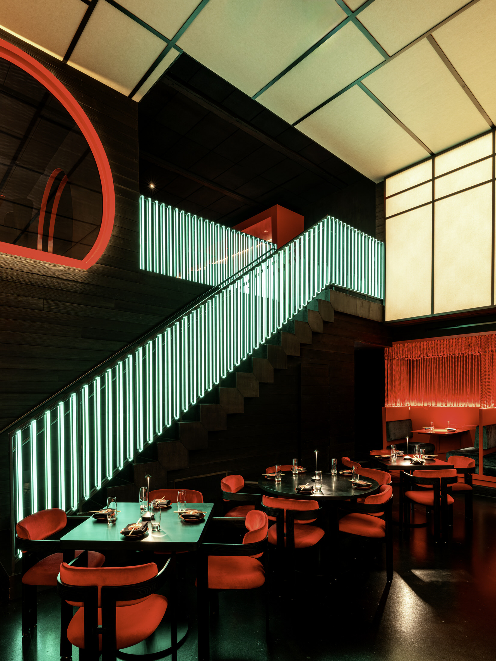 An inverted bonsai tree suspended from a polished red disc above a bar.