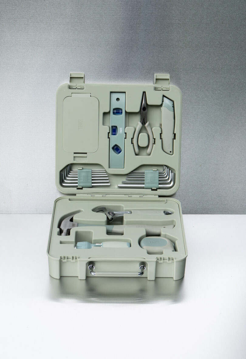 An open mint green plastic toolbox displaying a neatly organized hammer, pliers, and measuring tape.