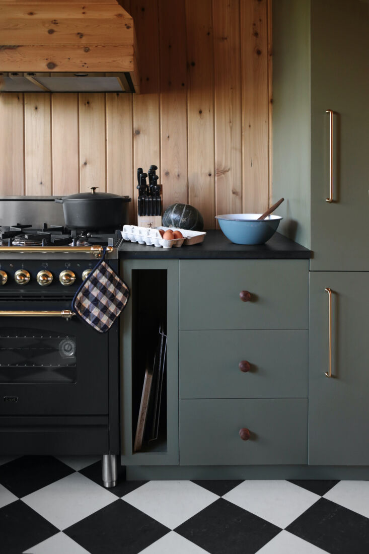 A matte graphite Ilve Nostalgie range set against dark green cabinets.