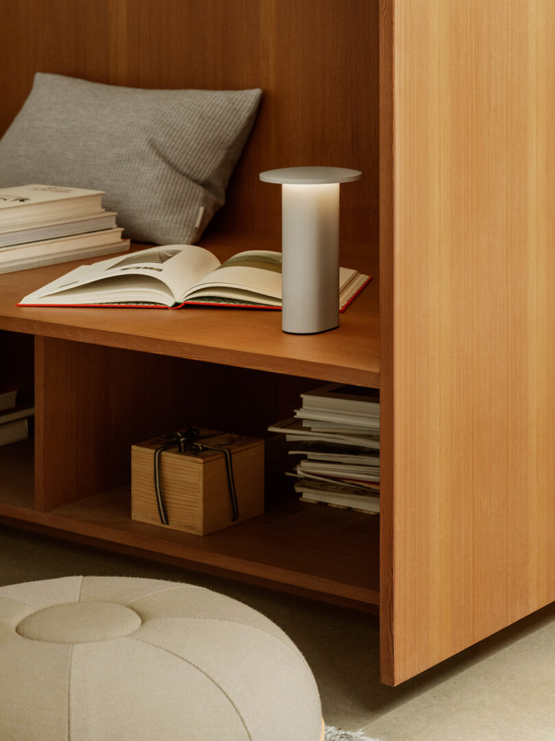 A white Solae lamp placed next to an open book on a wooden shelf.