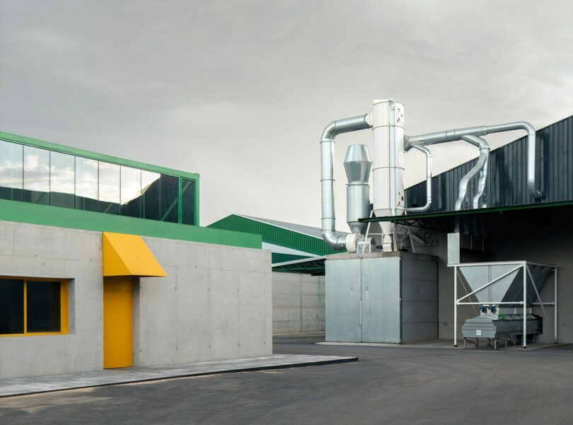 Exterior view of an industrial facility with silver ventilation ducts and a green metal roof.