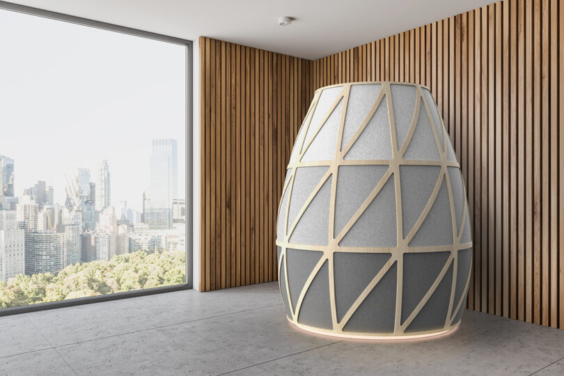 A geometric Iris meditation pod positioned in a modern office with large windows.