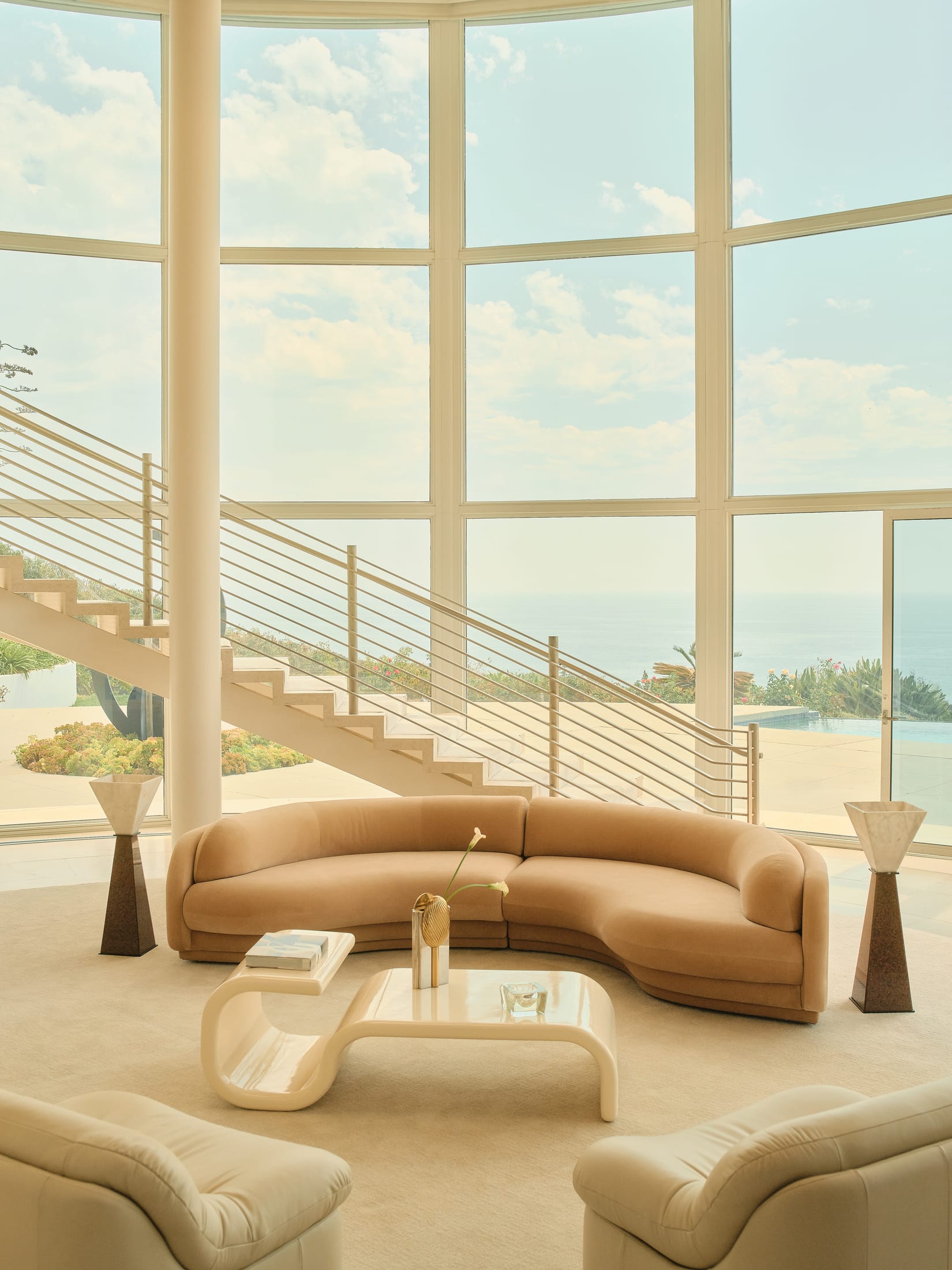 A styled interior featuring the Poet Sofa paired with sculptural lighting and a rounded coffee table.