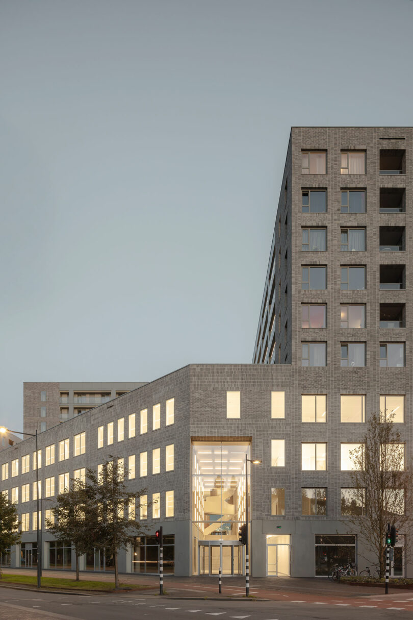 Night view of the 5TRACKS building with illuminated windows at a city intersection.