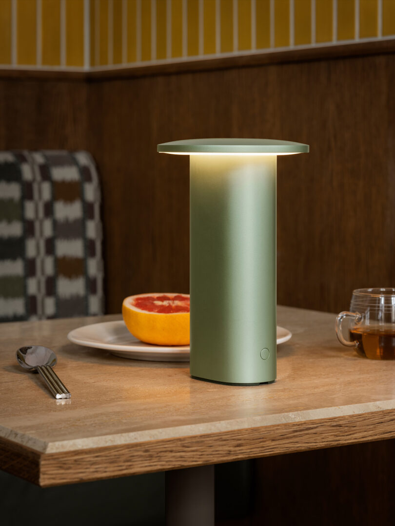 A green Solae lamp on a breakfast table with tea and a grapefruit.