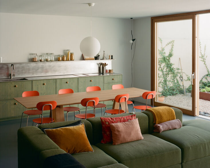 A long communal dining table set parallel to a single-wall kitchen layout.
