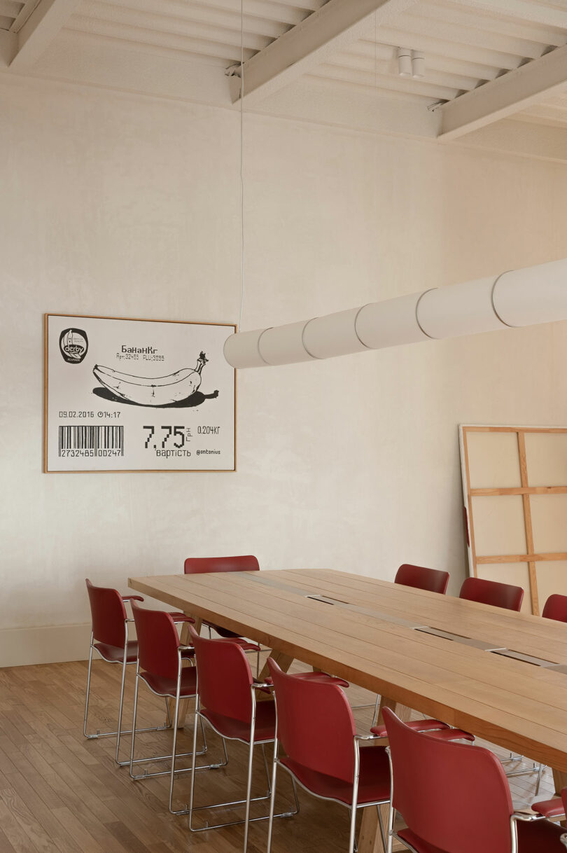 A meeting room featuring a long wooden table and large wall art of a banana with a barcode.