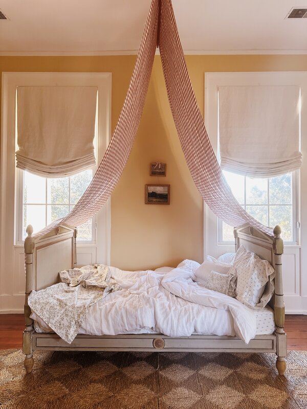 A rustic interior featuring vintage textiles, soft lighting, and floral arrangements in a cottage core style.