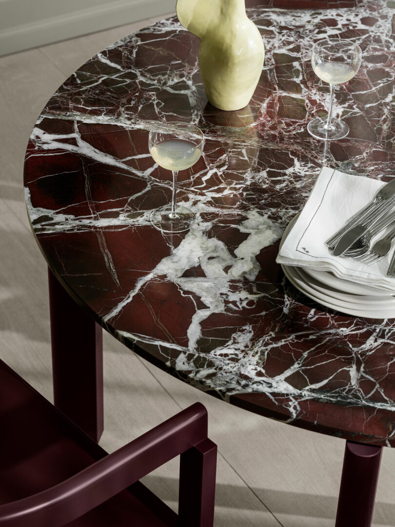 Top view of a round table with deep red and white marbled Rosso Levanto stone and burgundy wood trim.