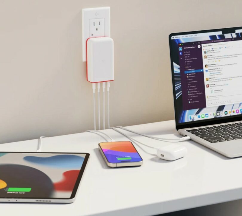 A high-powered charging hub connected to a laptop, tablet, and smartphone on a minimalist desk.