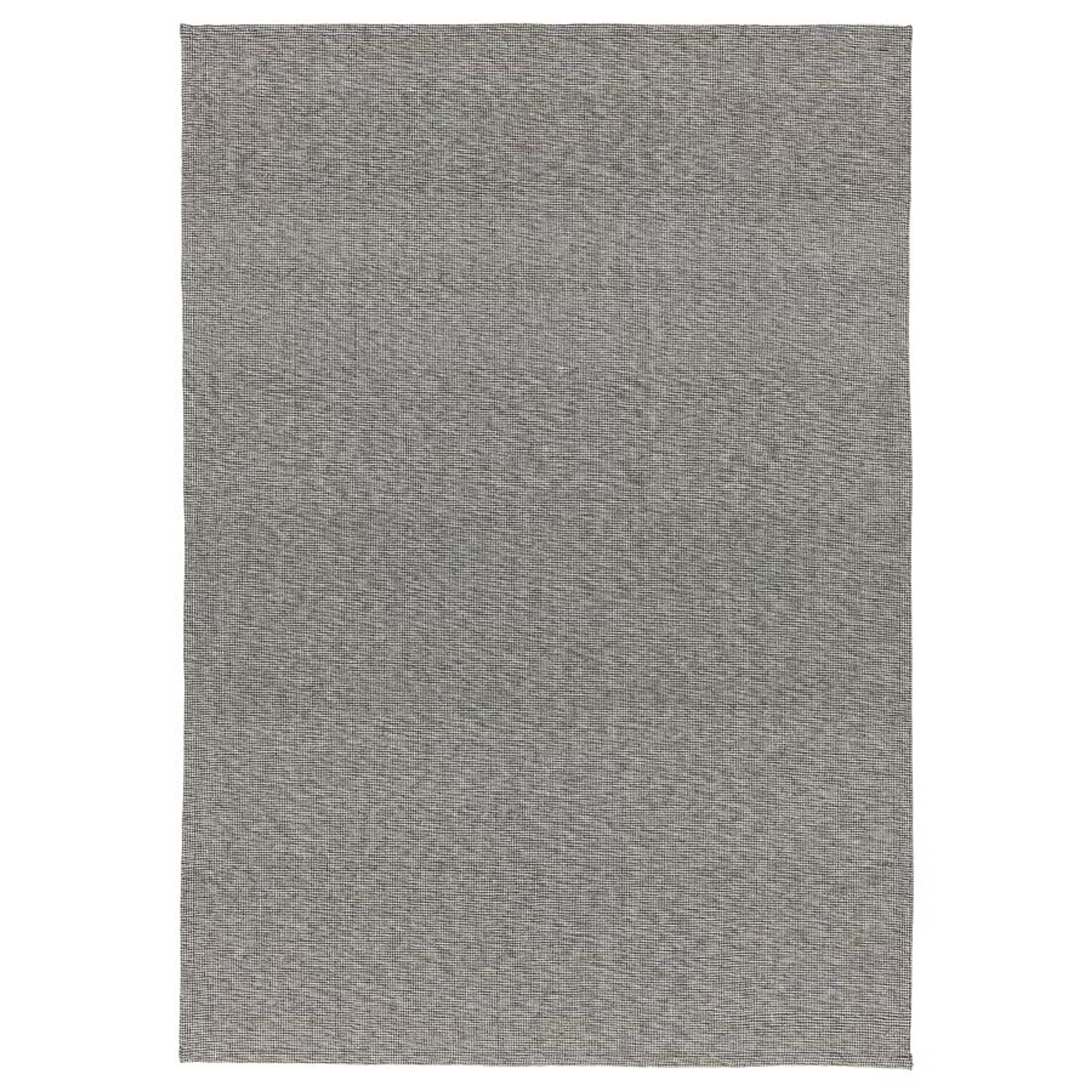 A simple gray cotton rug from Ikea placed in a clean, minimalist setting.
