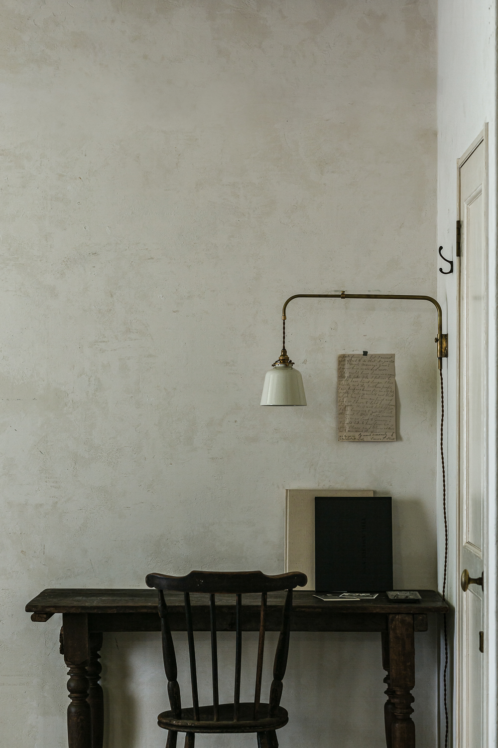 A brass Hanger Mini light with a movable arm and a white enamel shade.