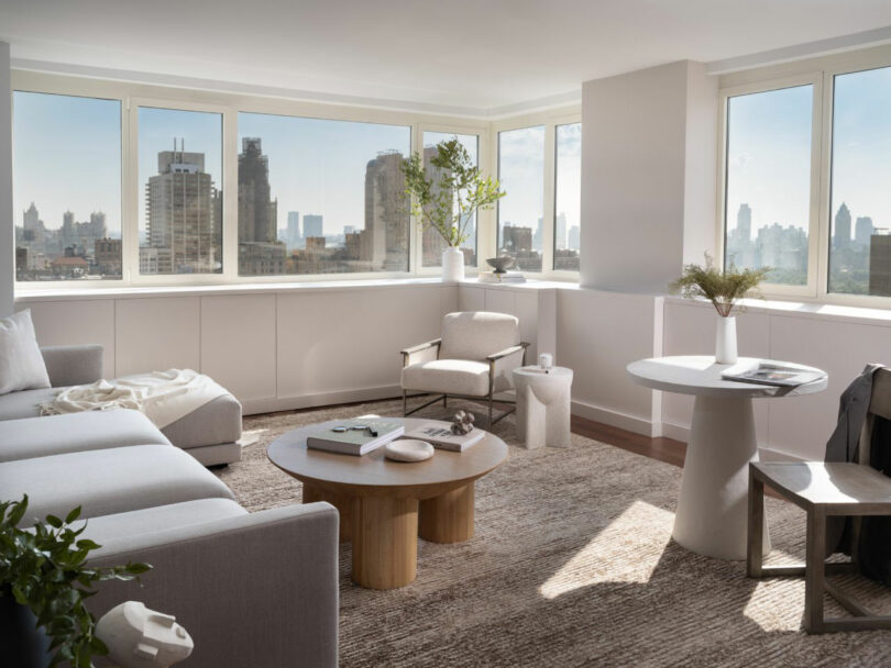 Bright living room featuring a city view, light wood furniture, and a minimalist gray sectional sofa.