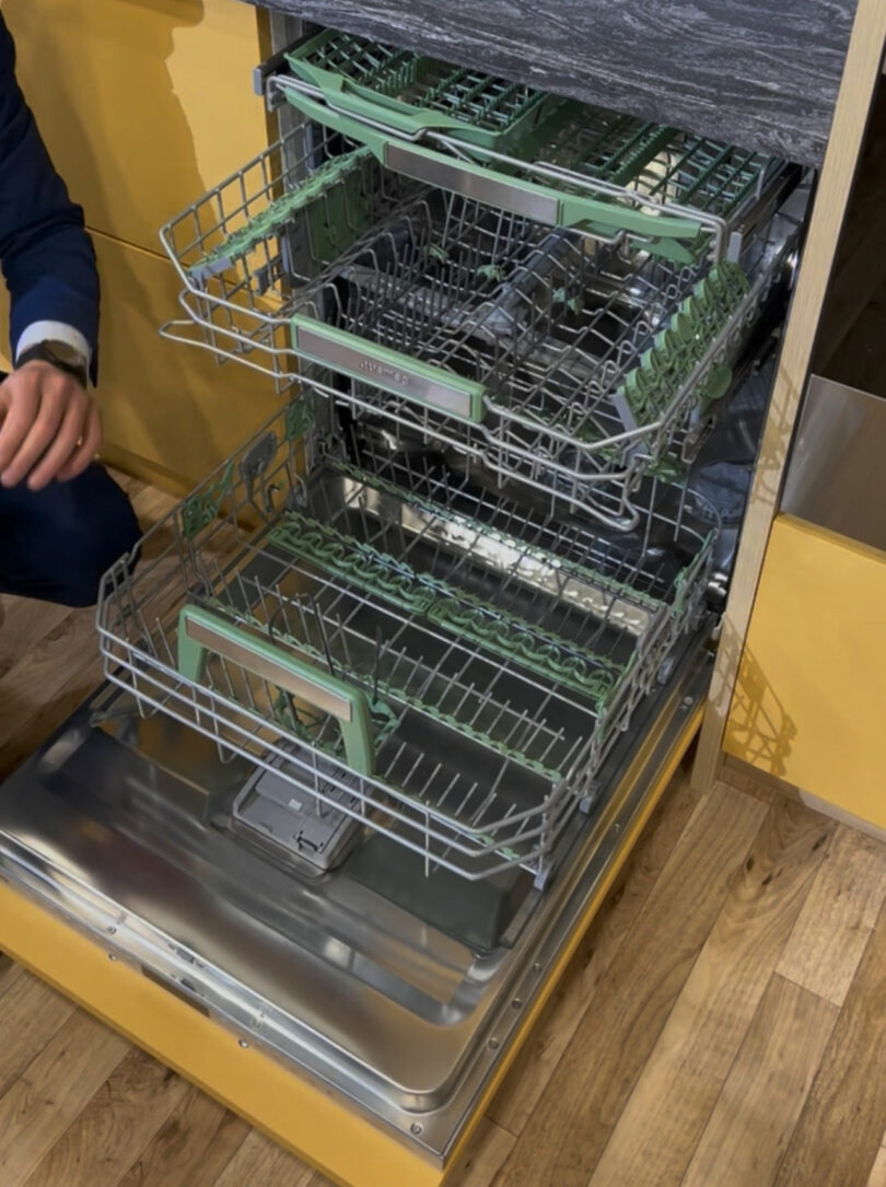 An open three-rack dishwasher showing the interior compartments and spray arms.