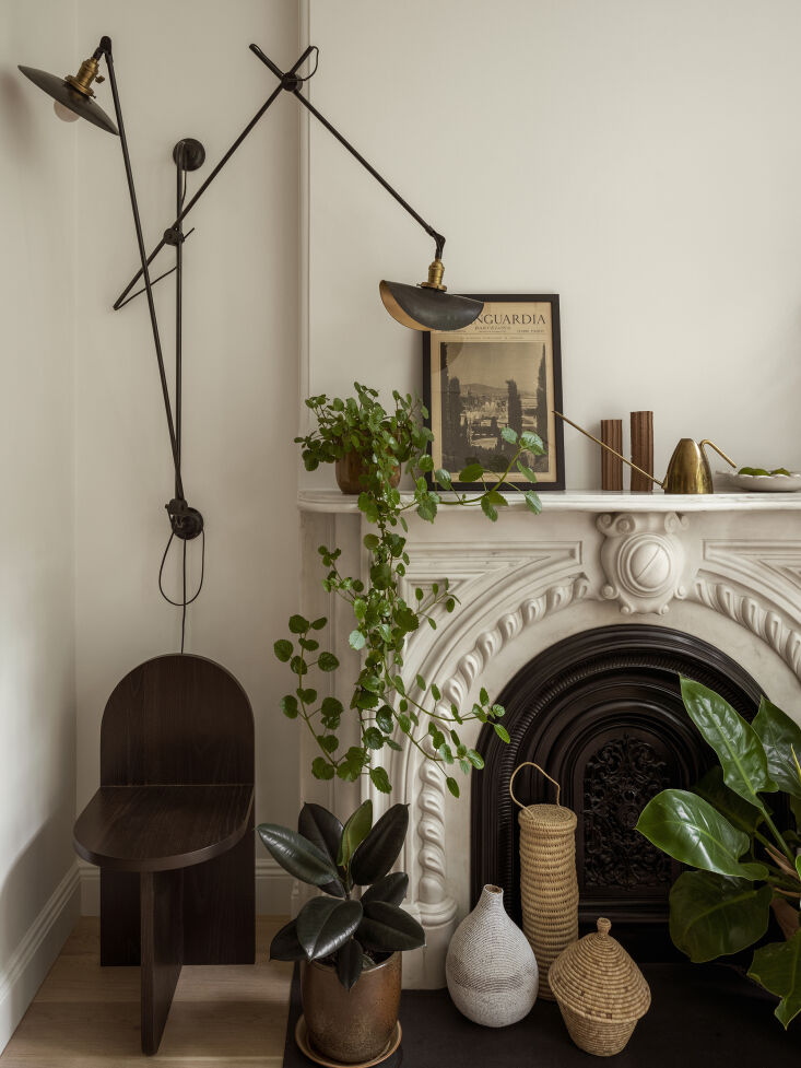 Historic stone mantel relocated to a modern kitchen with a minimalist black wall sconce.