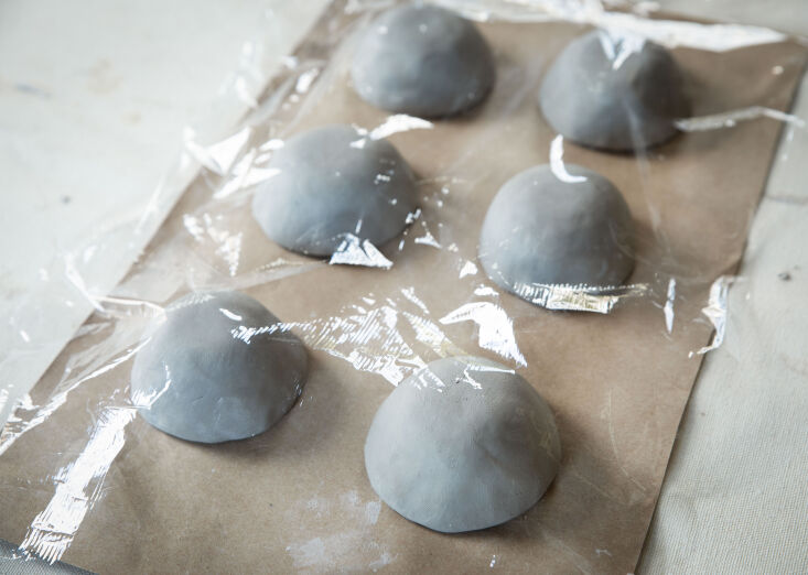 Clay votives covered loosely with plastic wrap to slow down the drying process.
